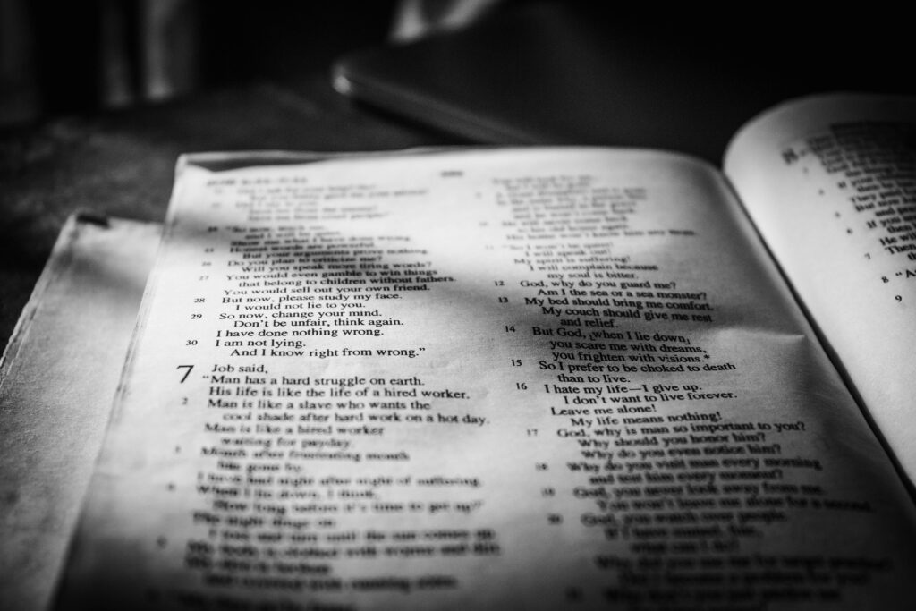 Close-up black and white photo of a Bible page with text in focus, creating a contemplative mood.